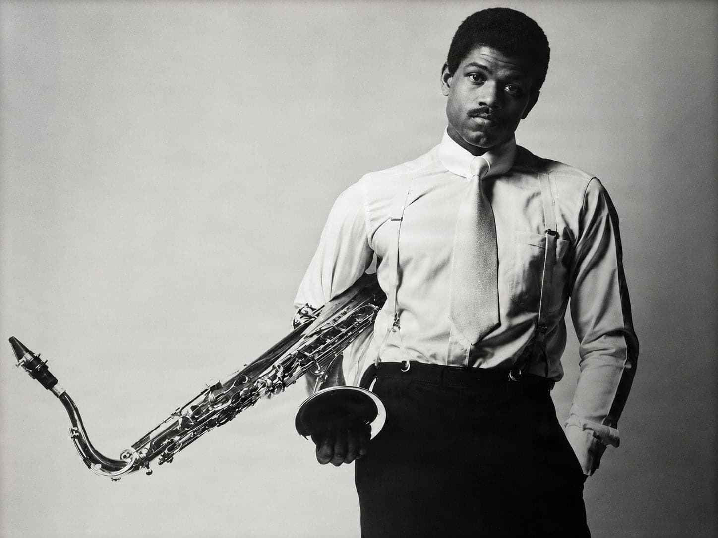 Man in Shirt and Suspenders Holds Saxophone in Studio Portrait