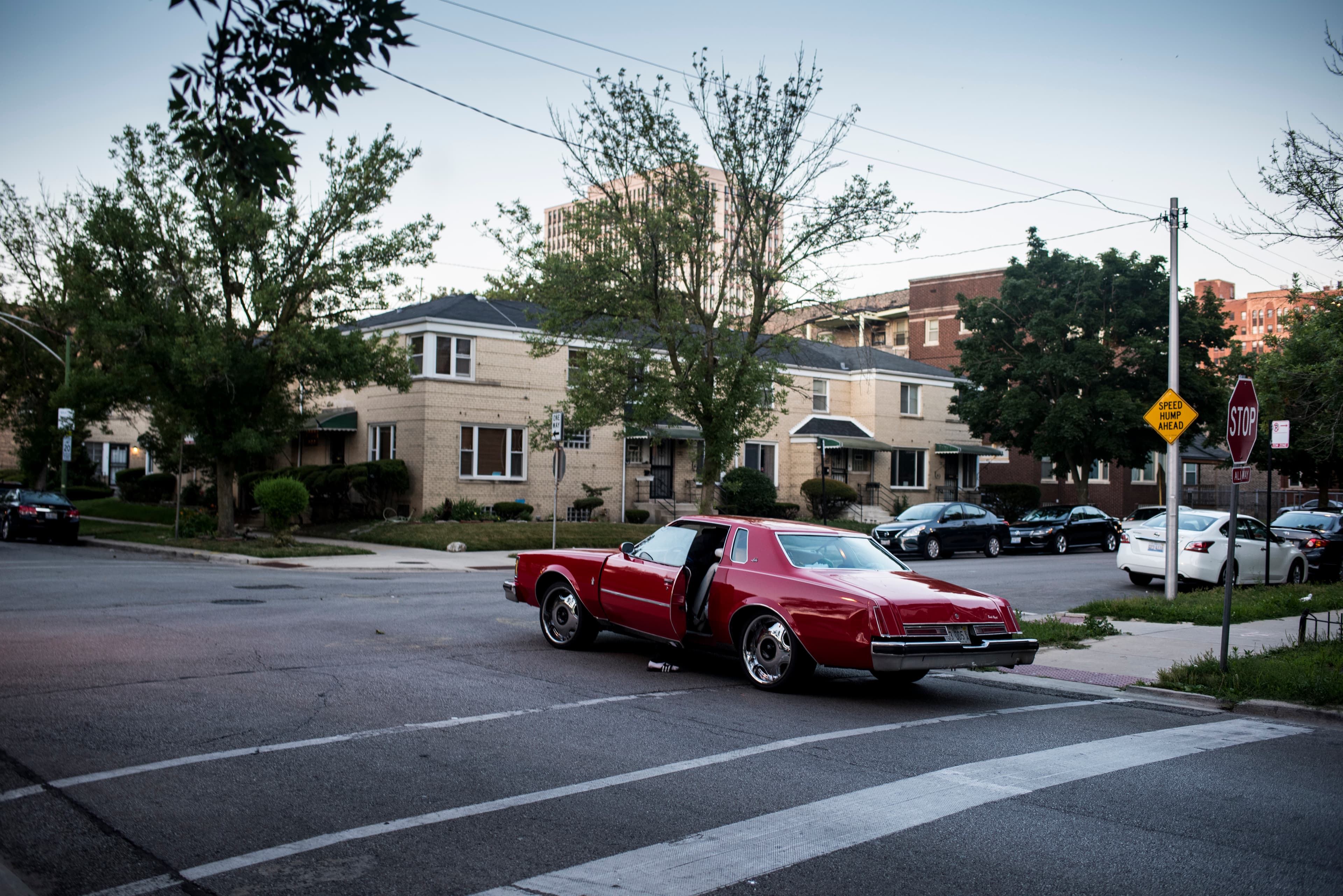 Red car with open door sits on urban street near residential buildings