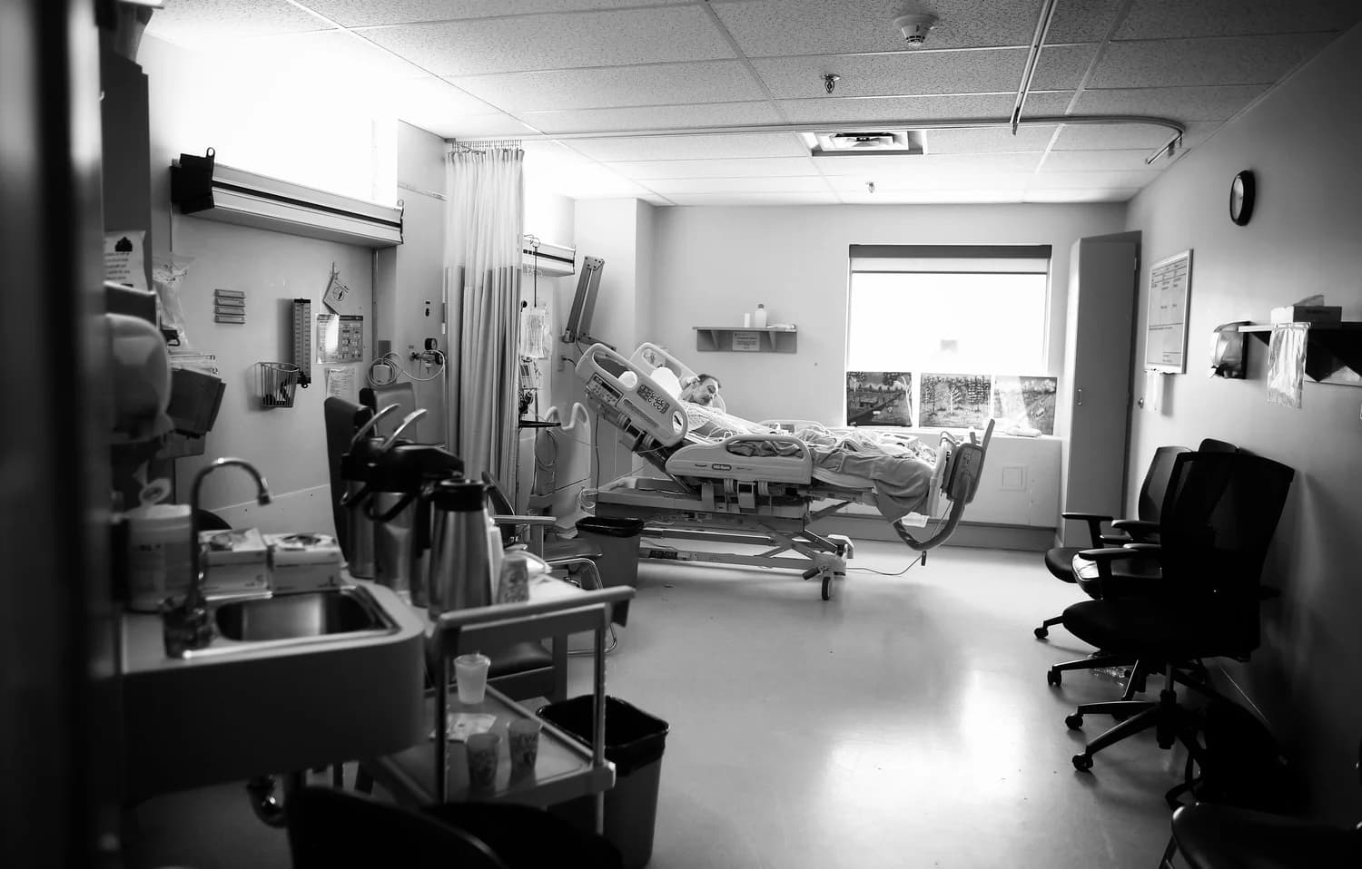 Patient rests in hospital bed within a medical room